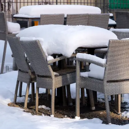 Verschneite Gartenmöbel aus Korbgeflecht im Winter