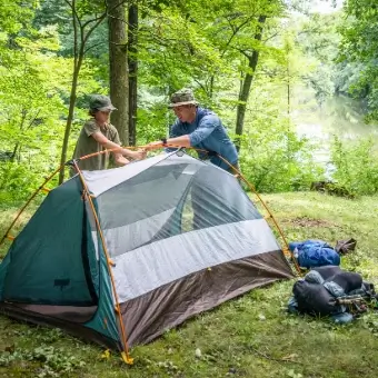 Camping Zelt Camping Zelt, das im Wald von einem Vater mit seinem Sohn zusammen gesteckt wird.
