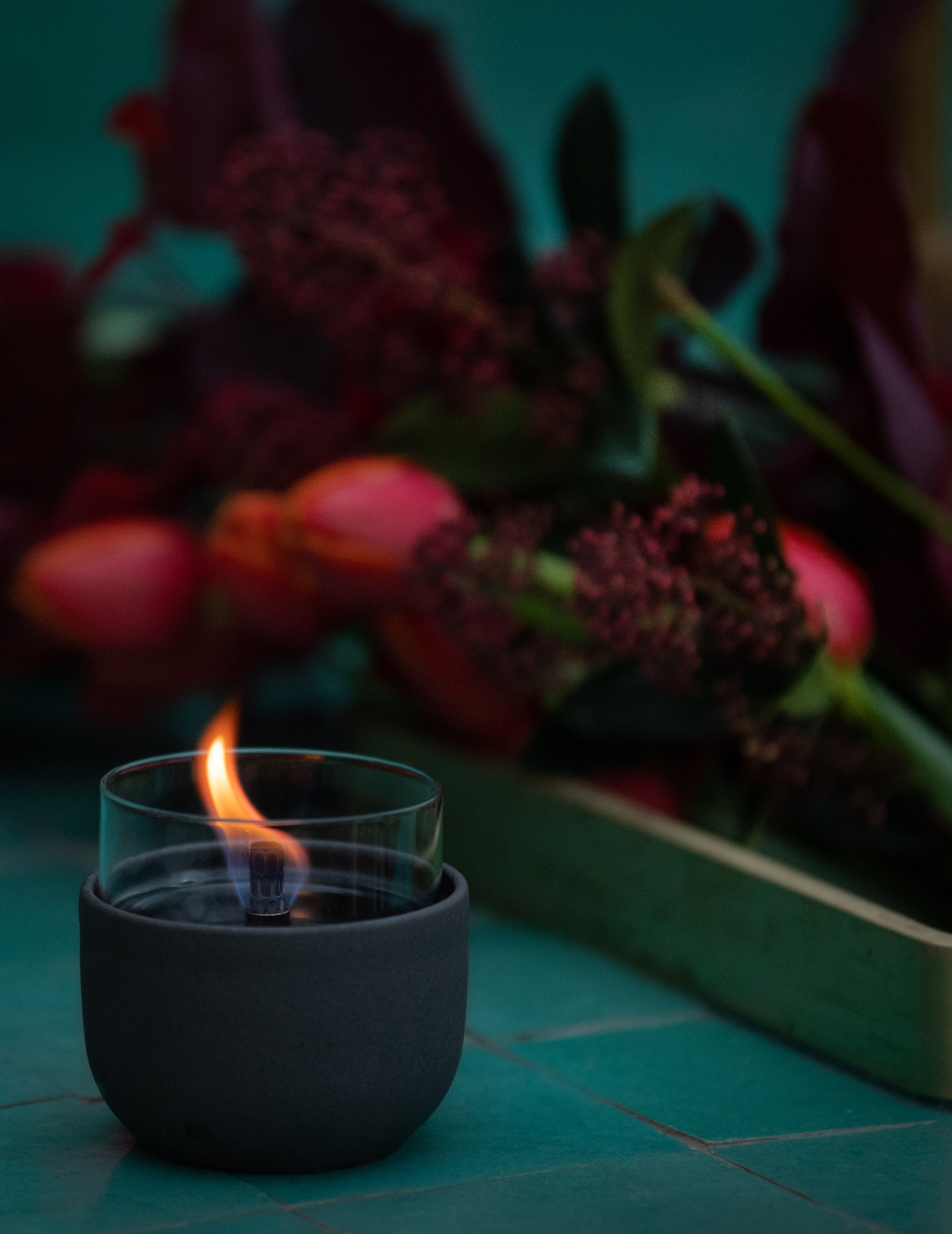 kleines vasenförmiges Tischfeuer in einem schwarzen Glashalter auf dunklem Hintergrund