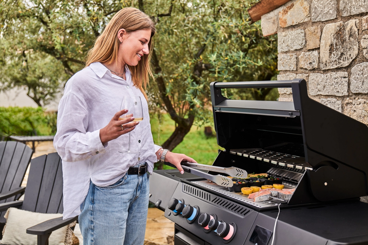 Frau mit Glas Wein an dem Grill