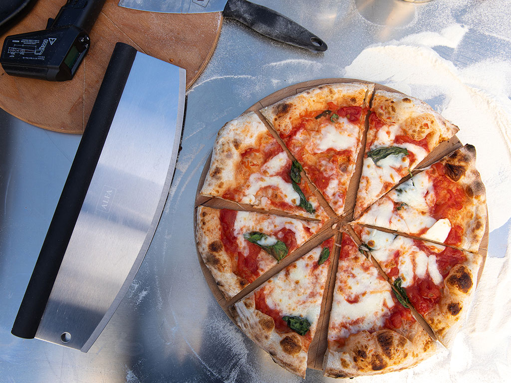 Alfa Forni Pizzaschneider Edelstahl neben Pizza geschnitten