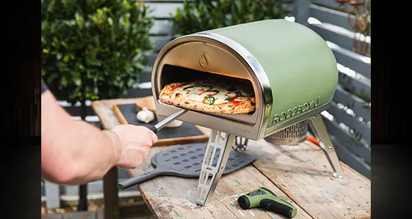 Gozney Roccbox Pizzaofen aus dem eine Pizza geholt wird